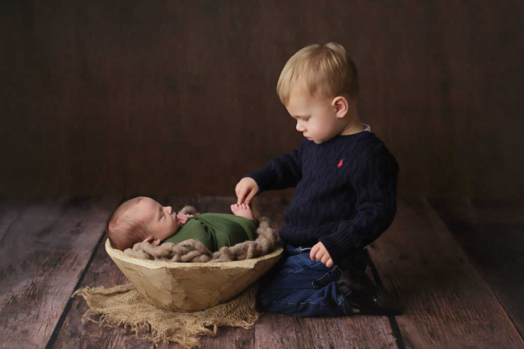 Brother touches his new baby brother's toes.